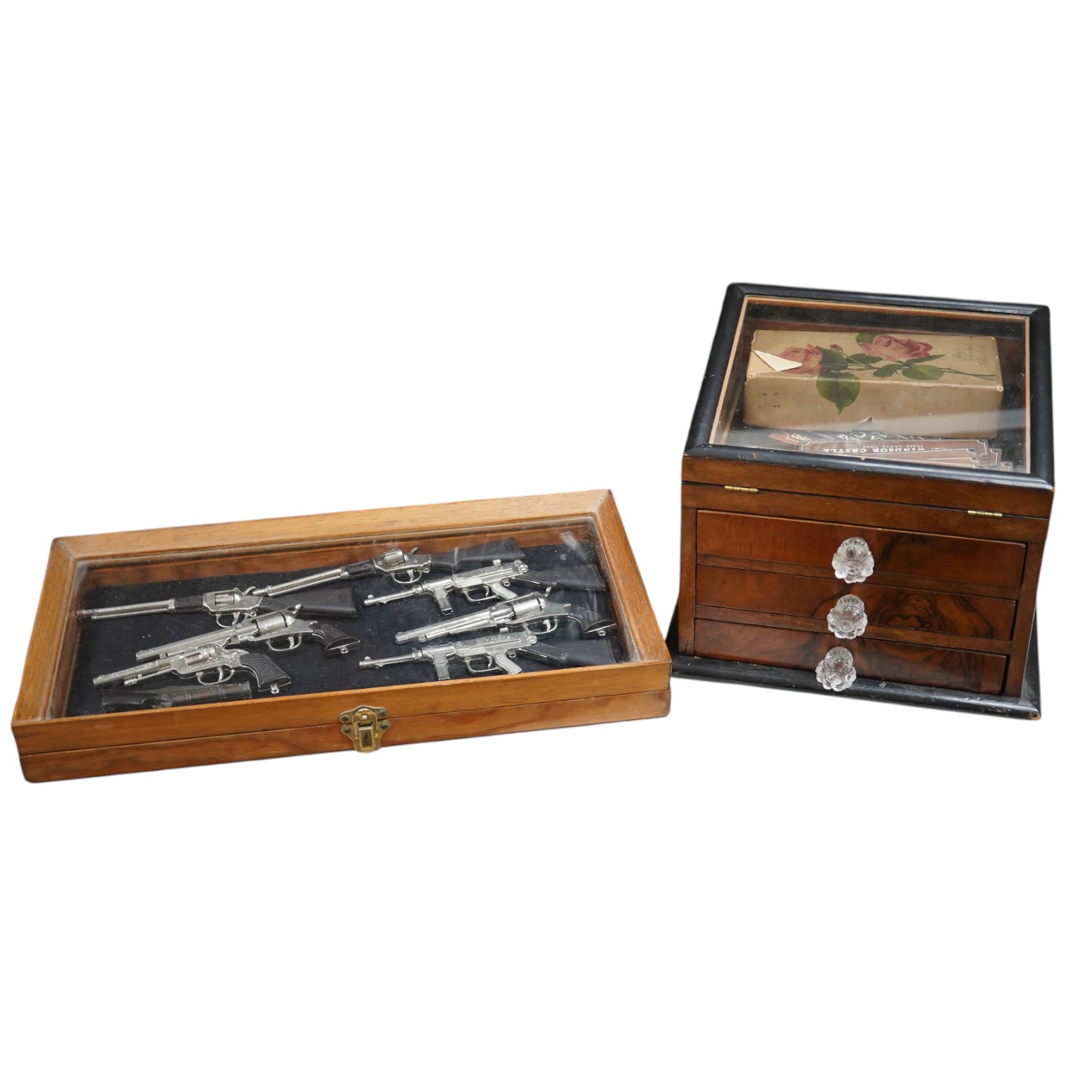 Sundry items comprising a small figured walnut table top collectors cabinet, a display case containing miniature rifles and pistols, a collection of copper and brass miniature RMS nameplates